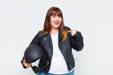 Artı cüsseli bir kadın mutlu, şaşırmış ve gururlu. Heyecanlı ve şaşkın bir bakışla kendini işaret ediyor.