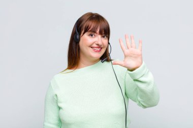 Artı, gülümseyen ve arkadaş canlısı görünen bir kadın. 5 ya da 5 numarayı gösteriyor. Eli önde, geriye doğru sayıyor.