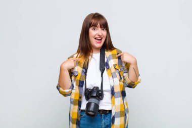 Artı cüsseli bir kadın mutlu, şaşırmış ve gururlu. Heyecanlı ve şaşkın bir bakışla kendini işaret ediyor.