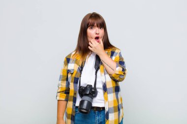 Artı, ağzı ve gözleri açık, elleri çenesinde, hoş olmayan bir şekilde şokta olan, ne ya da vay canına diyen boyunda bir kadın.