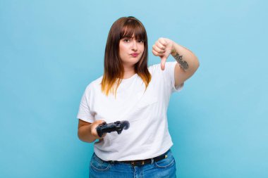 Artı boyut olarak, kızgın, sinirli, hayal kırıklığına uğramış ya da hoşnutsuz hisseden, ciddi bir bakışla başparmağını kaldıran bir kadın.