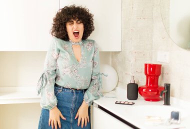 Genç ve güzel bir kadın agresif bir şekilde bağırıyor, kızgın, sinirli, öfkeli ya da sinirli görünüyor.