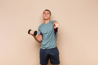 Genç sarışın adam kameraya bakıyor, kendinden emin, arkadaş canlısı bir gülümsemeyle, seni seçiyor.