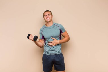 Genç sarışın adam komik bir şakaya yüksek sesle gülüyor, mutlu ve neşeli hissediyor, eğleniyor.