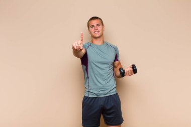 Genç sarışın adam gururla ve kendinden emin bir şekilde gülümsüyor. Bir numaralı pozunu başarıyla veriyor. Kendini lider gibi hissediyor.