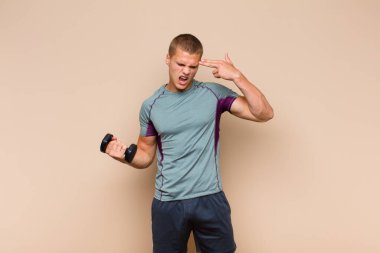 Genç sarışın adam mutsuz ve stresli görünüyor, intihar jesti elle silah işareti yapıyor, kafasını işaret ediyor.