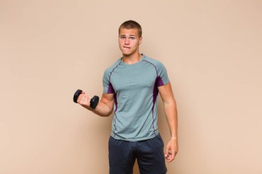 Genç sarışın adam şaşkın ve şaşkın görünüyor. Sinirli bir hareketle dudağını ısırıyor. Sorunun cevabını bilmiyor.