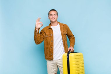 Genç sarışın adam mutlu, rahat ve tatmin olmuş hissediyor. Onayını iyi bir hareketle gösteriyor. Gülümsüyor.