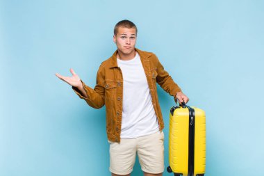 Genç sarışın adam şaşkın ve şaşkın hissediyor, şüpheci, farklı seçenekleri tartıyor veya komik bir ifadeyle seçiyor.