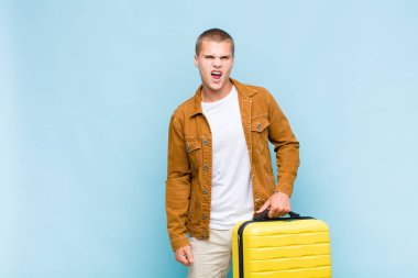 Genç sarışın adam agresif bir şekilde bağırıyor, çok kızgın, sinirli, öfkeli ya da sinirli görünüyor.