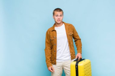 Genç sarışın adam şaşkın ve şaşkın görünüyor. Sinirli bir hareketle dudağını ısırıyor. Sorunun cevabını bilmiyor.