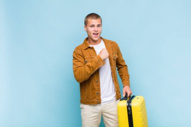 Genç sarışın adam mutlu, pozitif ve başarılı hissediyor, meydan okumayla karşılaştığında motive oluyor veya iyi sonuçları kutluyor.