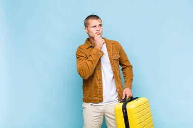 Genç sarışın adam düşünüyor, kuşkulu ve şaşkın hissediyor, farklı seçeneklerle, hangi kararı vereceğini merak ediyor.