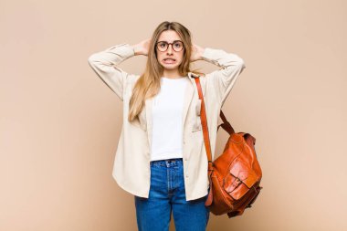 Sarışın, güzel bir kadın kendini stresli, endişeli, endişeli ya da korkmuş hissediyor. Elleri başının üstünde, hatayla panikliyor.