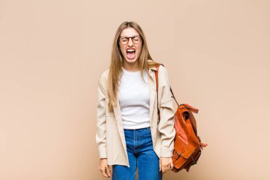 Sarışın, güzel bir kadın agresif bir şekilde bağırıyor, çok sinirli, sinirli, öfkeli ya da sinirli görünüyor.