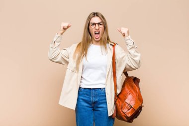 Sarışın, güzel bir kadın sinirli bir ifadeyle bağırıyor ya da yumruklarıyla başarıyı kutluyor.