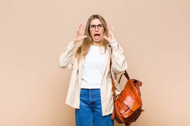 Sarışın, güzel bir kadın elleri havada bağırıyor. Öfkeli, sinirli ve üzgün.