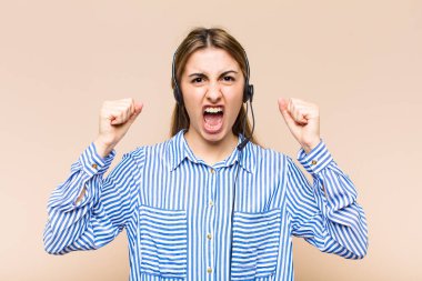 Sarışın, güzel bir kadın sinirli bir ifadeyle bağırıyor ya da yumruklarıyla başarıyı kutluyor.