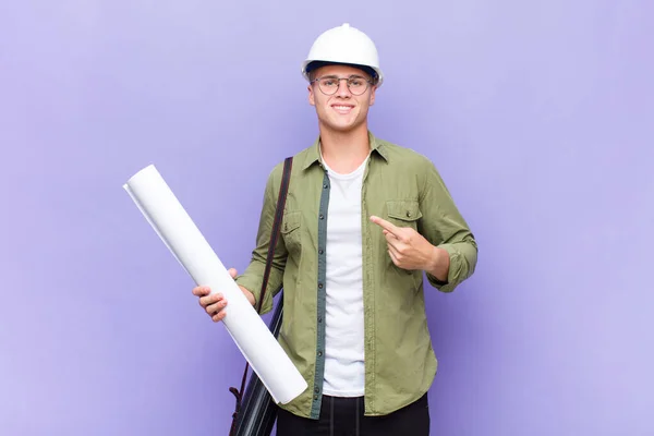 Joven Hombre Rubio Sonriendo Alegremente Sintiéndose Feliz Señalando Hacia Lado —  Fotos de Stock