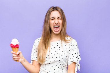 Sarışın, güzel bir kadın agresif bir şekilde bağırıyor, çok sinirli, sinirli, öfkeli ya da sinirli görünüyor.