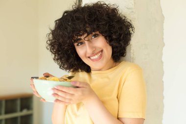 Genç ve güzel bir kadın kahvaltısını evde yapıyor.