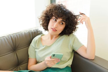 Genç ve güzel bir kadın yeni evinde akıllı telefonunu kullanıyor.