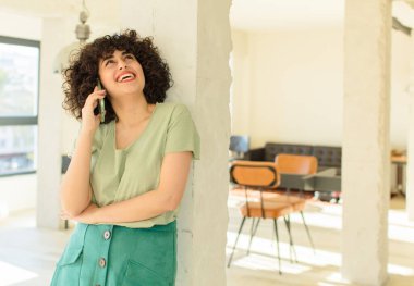 Genç ve güzel bir kadın yeni evinde akıllı telefonunu kullanıyor.