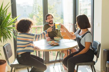 Bir grup arkadaş yeni evlerinde kahvaltı ediyorlar.