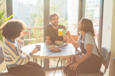 Bir grup arkadaş yeni evlerinde kahvaltı ediyorlar.