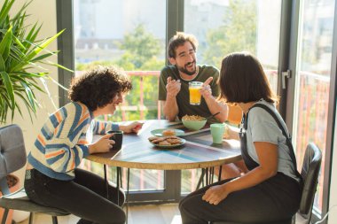Bir grup arkadaş yeni evlerinde kahvaltı ediyorlar.