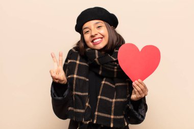 Genç ve güzel bir kadın elinde kalp kartı tutuyor.