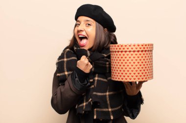 Genç ve güzel bir kadın elinde bir hediye tutuyor.