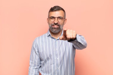 Yetişkin yakışıklı bir adam kameraya bakıyor, kendinden emin, arkadaş canlısı bir gülümsemeyle, seni seçiyor.