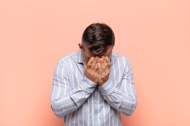 Yetişkin, yakışıklı bir adam üzgün, hayal kırıklığına uğramış, gergin ve depresif. İki eliyle yüzünü kapatıyor, ağlıyor.