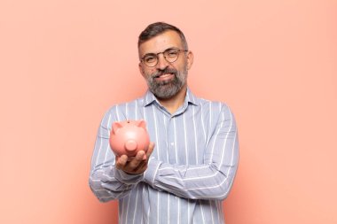 Yetişkin yakışıklı adam kollarını kavuşturup mutlu bir şekilde gülüyor, rahat, pozitif ve tatmin edici bir pozla.