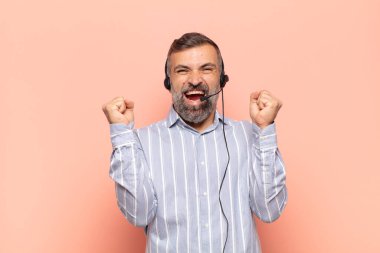 Yetişkin yakışıklı bir adam sinirli bir ifadeyle ya da yumruklarıyla başarıyı kutlarken agresif bir şekilde bağırıyor.