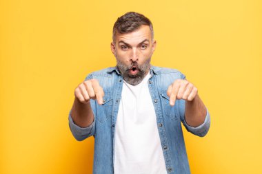 Yetişkin, yakışıklı bir adam şok olmuş, ağzı açık ve şaşkın, inançsızlık ve şaşkınlık içinde bakıyor ve onu işaret ediyor.