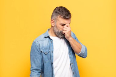 Yetişkin, yakışıklı bir adam stresli, mutsuz ve hayal kırıklığına uğramış, alınlı ve şiddetli baş ağrısı çeken.