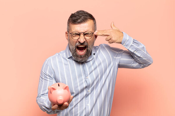 adult handsome man looking unhappy and stressed, suicide gesture making gun sign with hand, pointing to head