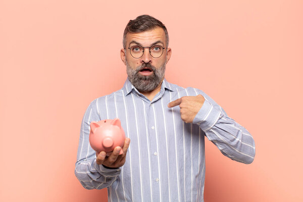 adult handsome man looking shocked and surprised with mouth wide open, pointing to self