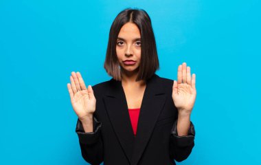 İspanyol kadın ciddi, mutsuz, kızgın ve hoşnutsuz görünüyor. Girmeyi yasaklıyor ya da her iki avuçta da dur diyor.