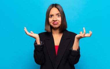 İspanyol kadın şaşkın, şaşkın ve stresli görünüyor, farklı seçenekler arasında merak ediyor, kararsız hissediyor.