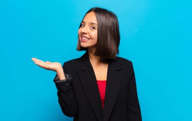 İspanyol kadın gülümsüyor, kendinden emin, başarılı ve mutlu hissediyor, fotokopi alanında fikir veya konsept gösteriyor.