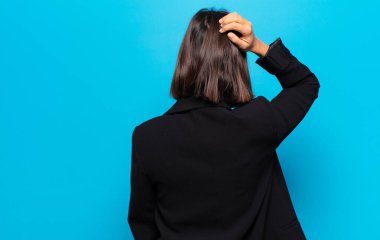 Hispanik kadın düşünüyor ya da şüphe ediyor, kafasını kaşıyor, şaşkın ve şaşkın hissediyor, arkaya ya da arkaya bakıyor.