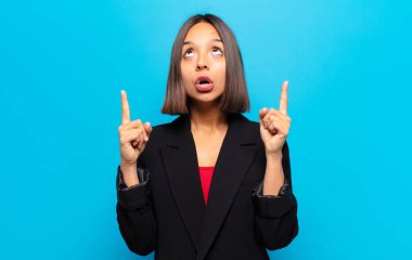 İspanyol kadın şaşırmış, şaşırmış ve ağzı açık bakıyor, iki eliyle uzayı işaret ediyor.