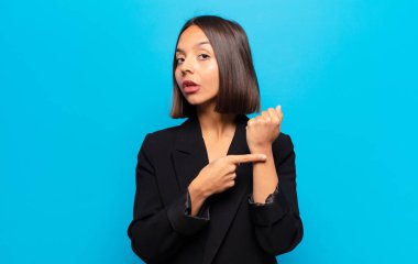 İspanyol kadın sabırsız ve kızgın görünüyor, saati gösteriyor, dakiklik istiyor, zamanında gelmek istiyor.