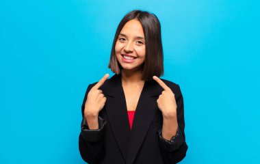 İspanyol kadın kendine güvenerek gülümsüyor. Kendi gülüşünü gösteriyor. Olumlu, rahat, tatmin olmuş tavır.