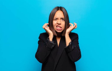 İspanyol kadın sinirli, stresli ve sinirli görünüyor, iki kulağını da sağır edici bir ses, ses ya da yüksek sesle kapatıyor.