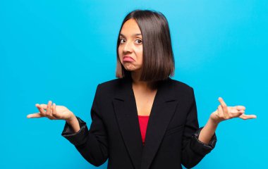 hispanic woman feeling clueless and confused, having no idea, absolutely puzzled with a dumb or foolish look