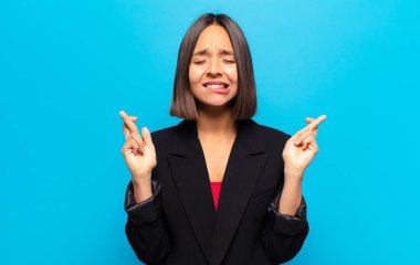 İspanyol kadın gülümsüyor ve endişeyle iki parmağını çapraz yapıyor. Endişeli ve iyi şanslar diliyor.